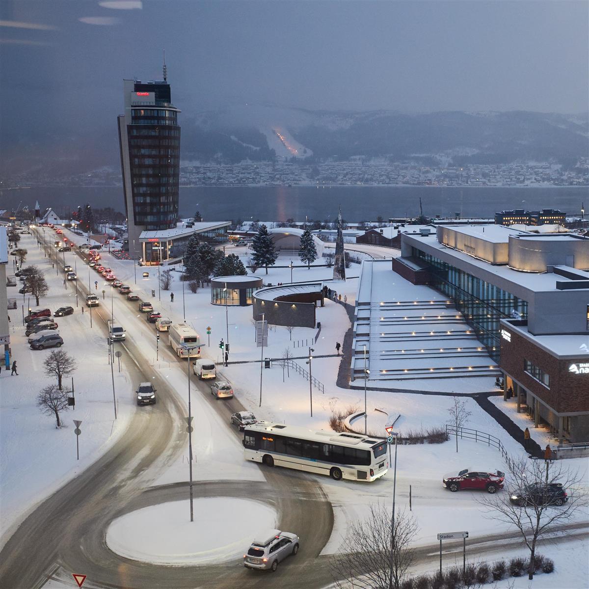 Oversiktsbilde av Narvik sentrum en vinterdag. På bildet ser man trafikk og rundkjøringen, og en buss som ikke er i trafikk. - Klikk for stort bilde